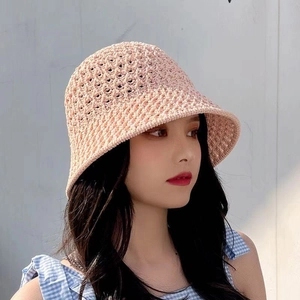 Detail view of the pink hollow-out knitted sun hat on a model with soft lighting