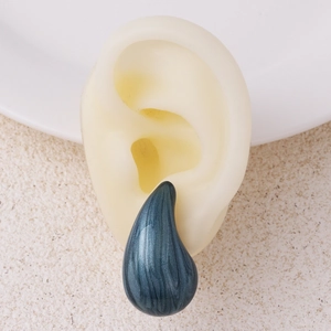 Detailed close-up of dark green teardrop earring with textured finish on model ear