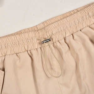 Close-up of elastic waistband with drawstring and metal stoppers on beige cotton pants
