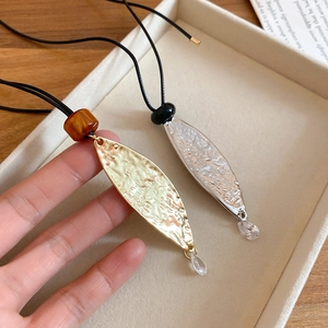 Detail of leaf pendants with hammered texture in gold and silver finishes