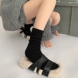 Close-up of black cross straps and off-white plush sole on stylish women's slippers