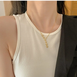 Detail of gold star tassel necklace featuring micro-zirconia stones on a female model