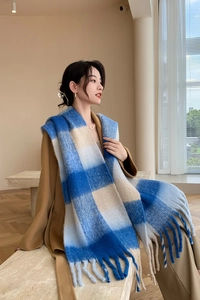 Détail de l'écharpe à carreaux bleu et beige montrant les franges et la texture laineuse
