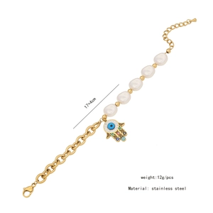 Detail of stainless steel bracelet with pearls and a turquoise Hamsa Hand pendant