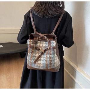 Detail showing vintage plaid wool backpack with brown leather straps worn by model