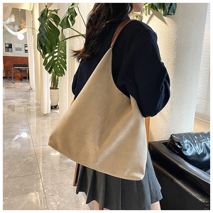 Detail of the suede texture and spacious interior of the beige tote bag on model