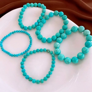 Detail of turquoise bead bracelets in various sizes on a white plate with velvet background
