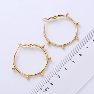 Detail of 3cm golden hoop earrings with bead accents and size reference scale