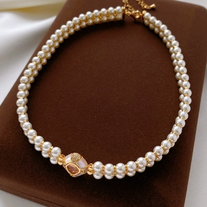 Vue détaillée du collier de perles plaqué or avec pendentif carré sur support brun