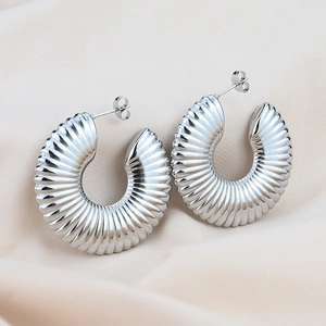 Macro shot of silver C-shaped hoop earrings with textured pleated metal details