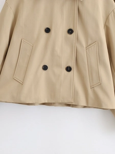 Close-up of khaki trench coat showing double-breasted black buttons and pocket stitching