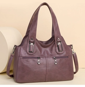 Detail view of burgundy faux leather handbag with silver zippers and adjustable strap