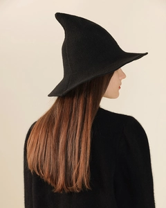 Detail view of the black knitted wool pointed witch hat with texture on neutral background