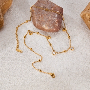 Golden necklace with zircon pendant elegantly styled on natural stone texture background