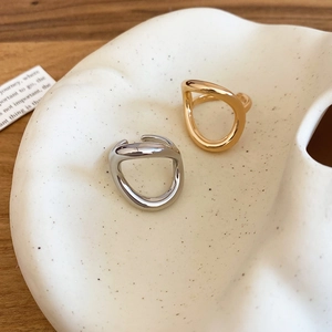 Close-up of gold and silver irregular geometric metal rings on a white ceramic dish