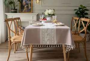 Detail of pink Christmas tablecloth featuring deer knit patterns and ivory fringe edges