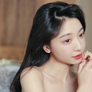Elegant silver heart stud earrings with sparkling crystals shown on a model's ear