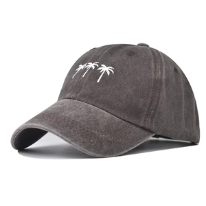 Close-up of white palm tree embroidery on a washed charcoal grey cotton baseball cap