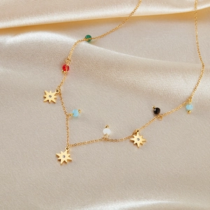 Macro shot of gold stainless steel necklace with colorful beads and star pendants on silk