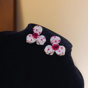 Détail de boucles d'oreilles fleur avec cristal rouge et pavé de diamants brillants