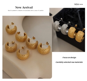 Detail shot of gold and silver C-shaped earrings with intricate woven texture and glossy finish