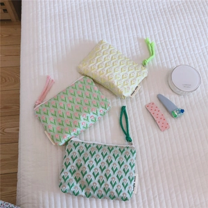 Vue détaillée des pochettes fleuries en jacquard pour cosmétiques sur literie blanche