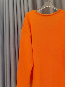 Gros plan du pull en tricot orange vif à col en V avec texture côtelée verticale
