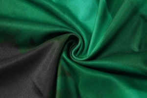 Dettaglio macro del tessuto twill verde smeraldo e nero con morbido drappeggio e lucentezza