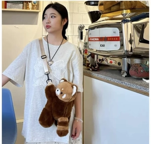 Detailed view of plush red panda crossbody bag with adjustable beige strap on model