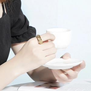 Golden heart ring with small diamonds shown in a lifestyle scene with a coffee cup