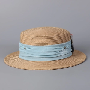 Détail d'un chapeau de paille à sommet plat avec tissage fin et ruban bleu clair orné de strass