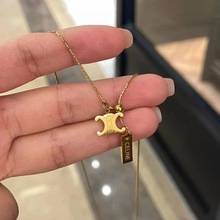 Detail of gold chain necklace featuring Triomphe logo and branded rectangular metal tag