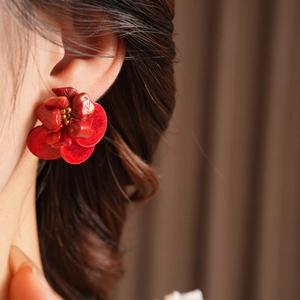 Close-up of red flower earrings made of faceted stones with a gold center bead