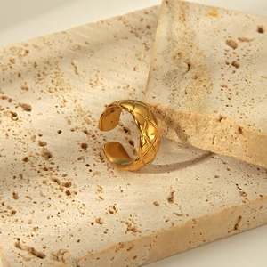 Close-up of golden hammered texture open ring on minimalist travertine stone background