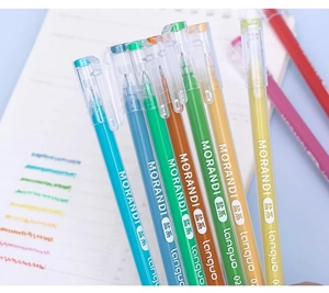 Close-up of Morandi color gel pens set on a notebook and blue desk surface
