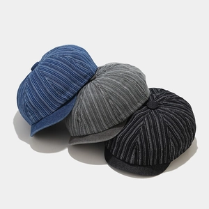 Close-up of washed denim newsboy caps in blue, gray and black with ribbed fabric texture