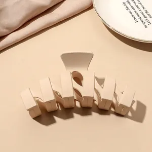 Macro detail of matte beige shark hair claw clip on pink silk background