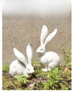Detalle de dos estatuas de conejo de resina estilo vintage con acabado envejecido en césped