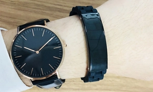 Close-up of black silicone bracelet and minimalist watch on wrist over wood desk