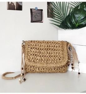 Detail of hand-woven straw crossbody bag with intricate textures and wooden bead strap