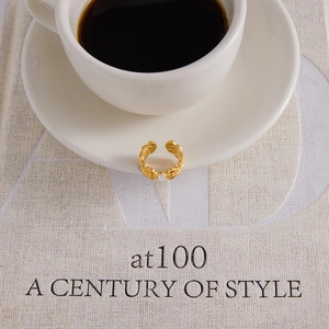 Close-up of a vintage gold open ring with an elegant white pearl on a coffee cup
