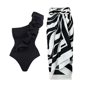 One-shoulder black ruffled swimsuit with a zebra print sarong wrap for a beach resort look