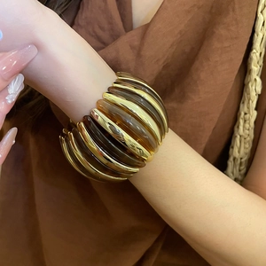 Close-up of a wide resin and gold metal striped bracelet on a model's wrist