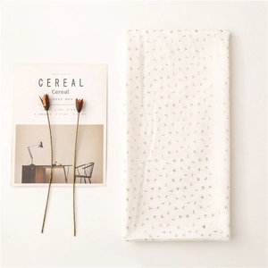 Close-up of white voile scarf with gold leaf print and elegant magazine background
