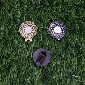 Three magnetic golf hat clips in gold, dark grey, and black on green grass background