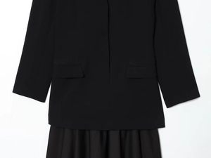Detailed view of women's black blazer dress featuring side flap pockets and pleated hemline