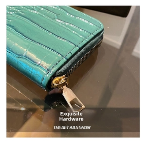 Macro shot of gold zipper hardware and emerald green crocodile leather on the clutch bag