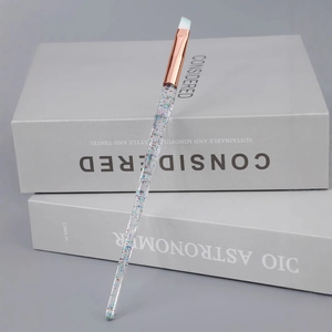 Angled eyebrow brush with crystal glitter handle and soft white synthetic bristles