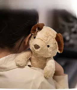 Close-up of soft plush dog toy in beige with brown ears and gentle furry texture