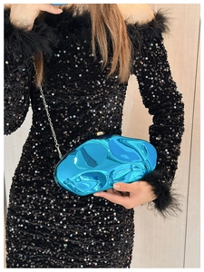 Detail of blue metallic wave-shaped clutch bag with silver chain and sphere clasp